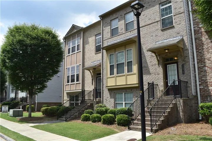 Brick facade townhome featuring a decorative bay window and an inviting entryway with an awning