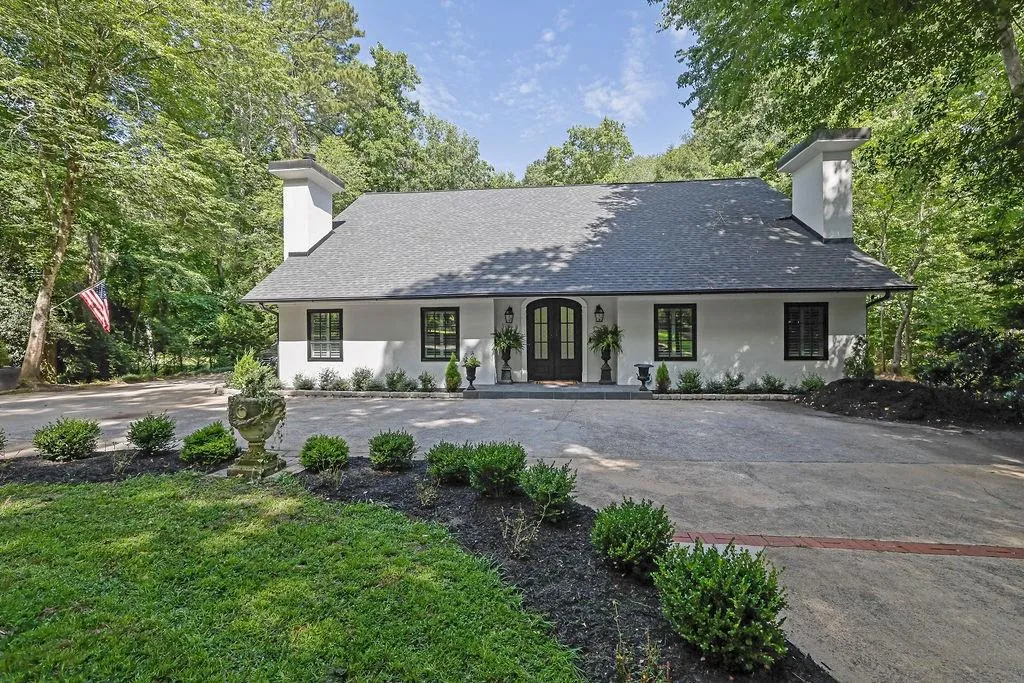 View of front of home with a chimney, covered porch, driveway, and stucco siding