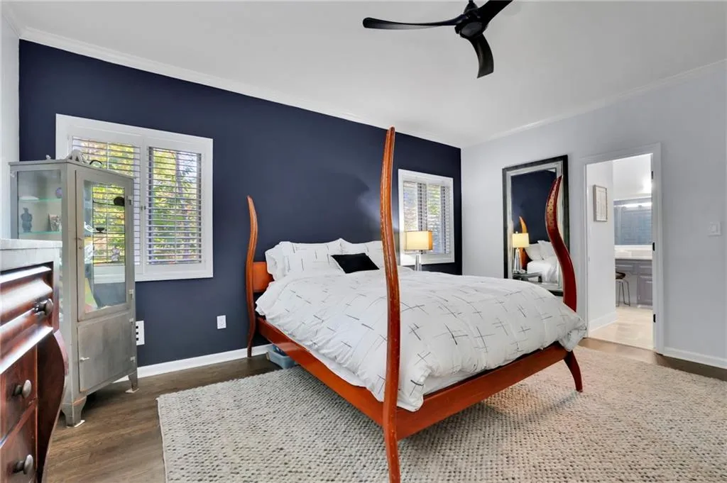 Bedroom featuring ornamental molding, wood finished floors, a ceiling fan, and ensuite bath