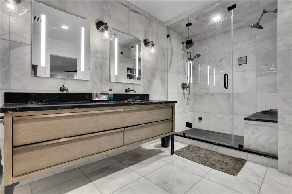 Bathroom featuring tile walls, double vanity, and a stall shower