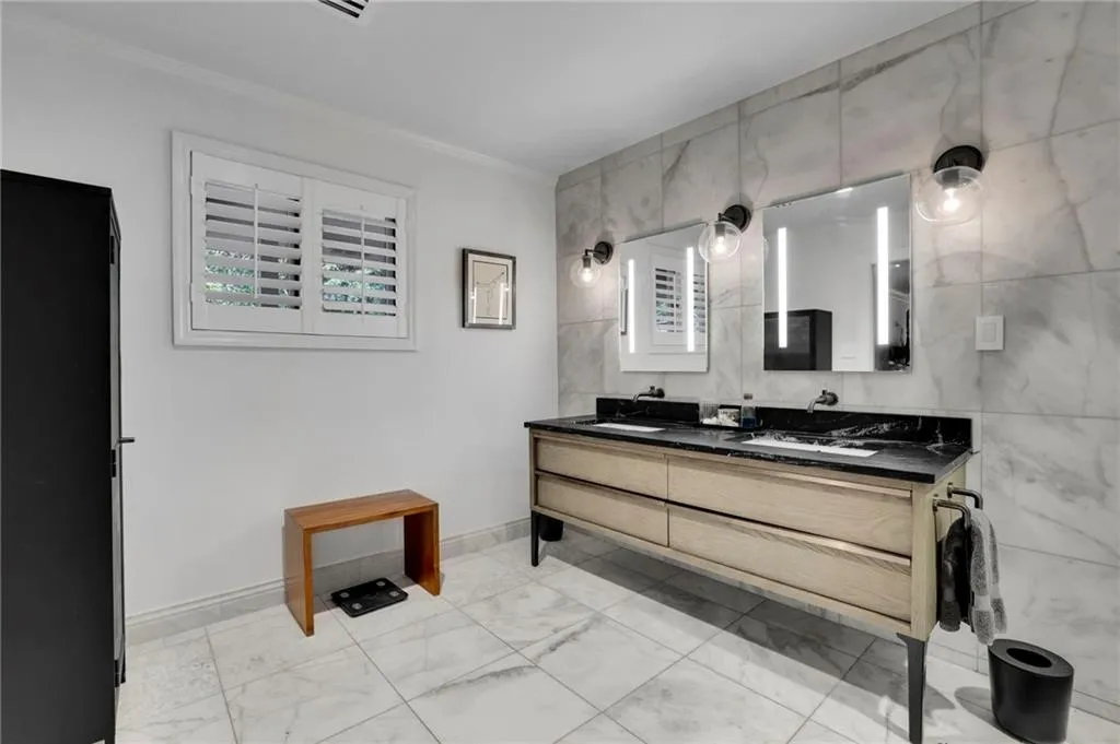 Bathroom featuring double vanity, tile walls, and ornamental molding