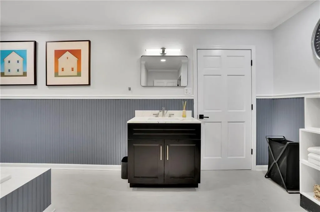 Bathroom featuring ornamental molding, vanity, a wainscoted wall, and a bathtub