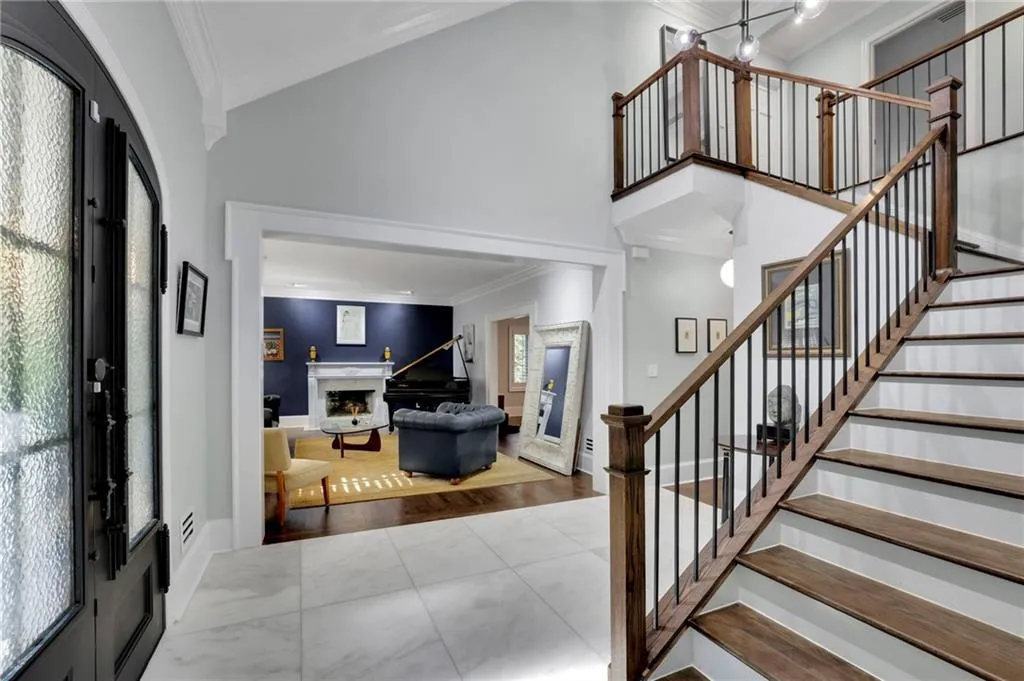 Foyer featuring crown molding, a towering ceiling, a fireplace, and stairway