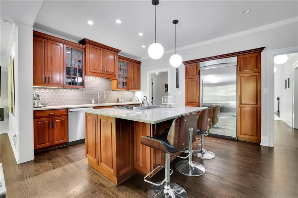 Kitchen featuring backsplash, a breakfast bar area, a center island, dark wood-style flooring, and glass insert cabinets