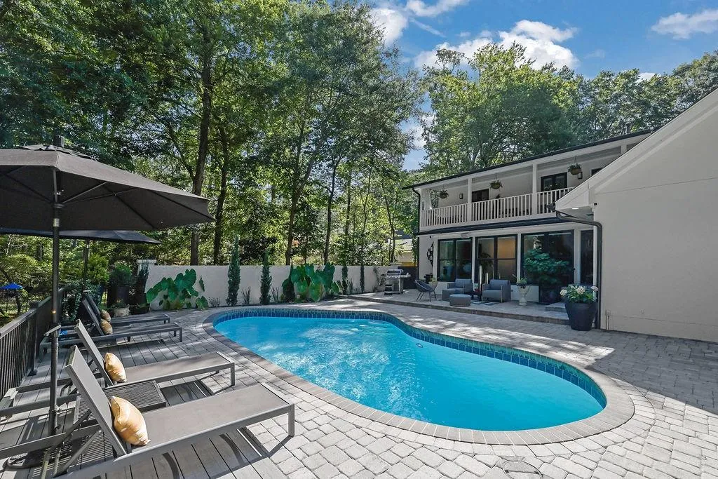 View of pool with a balcony, a patio area, a fenced backyard, and view of wooded area