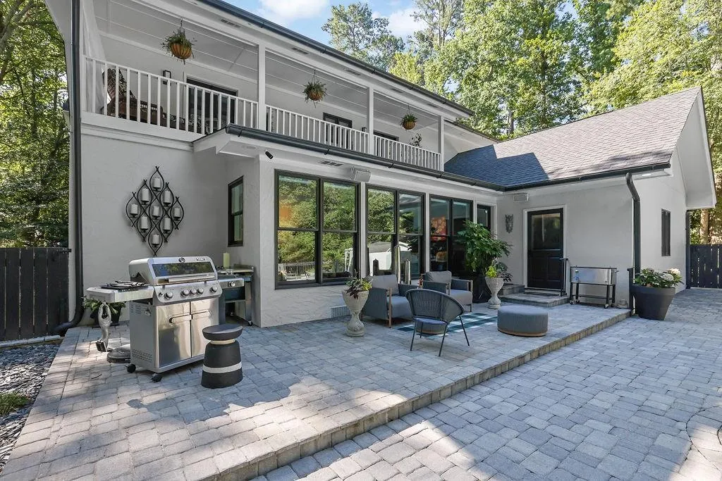 Rear view of property featuring a balcony, stucco siding, a patio, and a shingled roof