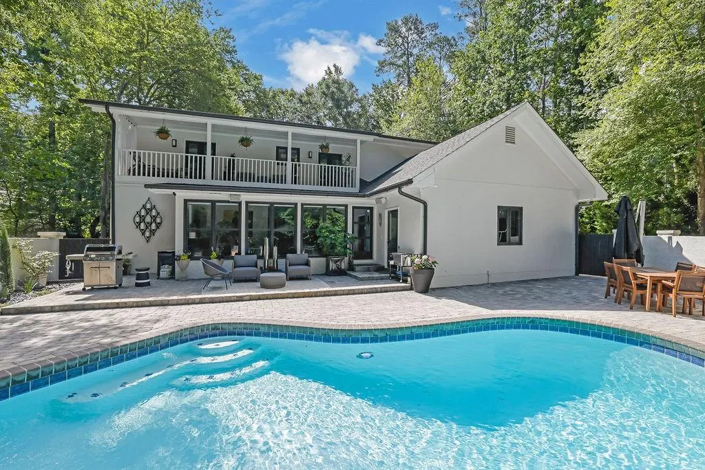 Back of property with a patio area, a balcony, stucco siding, and an outdoor pool