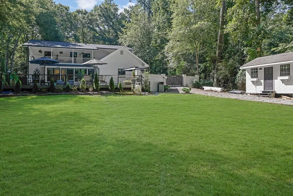 View of yard featuring an outdoor structure, a deck, view of scattered trees, and a balcony