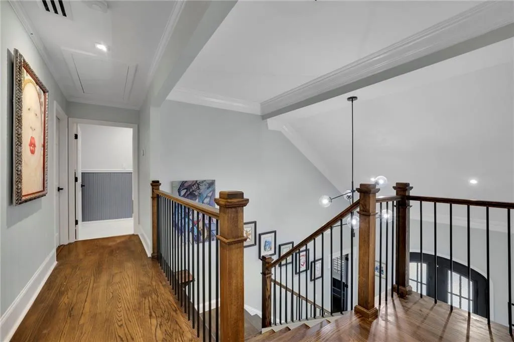 Hall with wood finished floors, ornamental molding, attic access, recessed lighting, and an upstairs landing