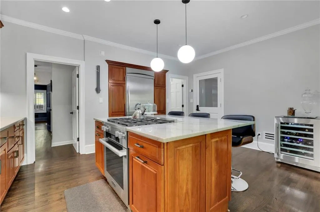 Kitchen with brown cabinets, appliances with stainless steel finishes, light stone counters, and backsplash