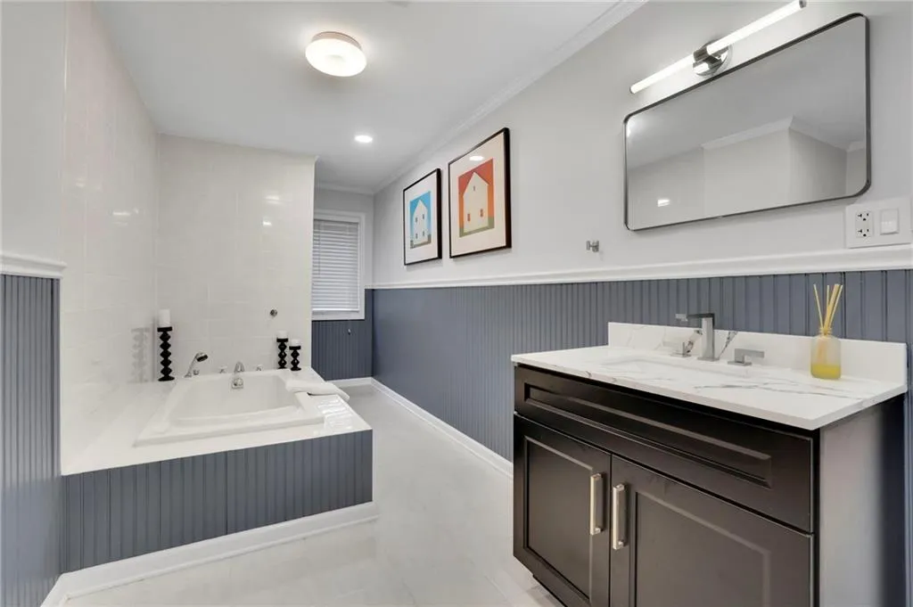 Bathroom featuring a garden tub, vanity, crown molding, wainscoting, and light tile patterned floors
