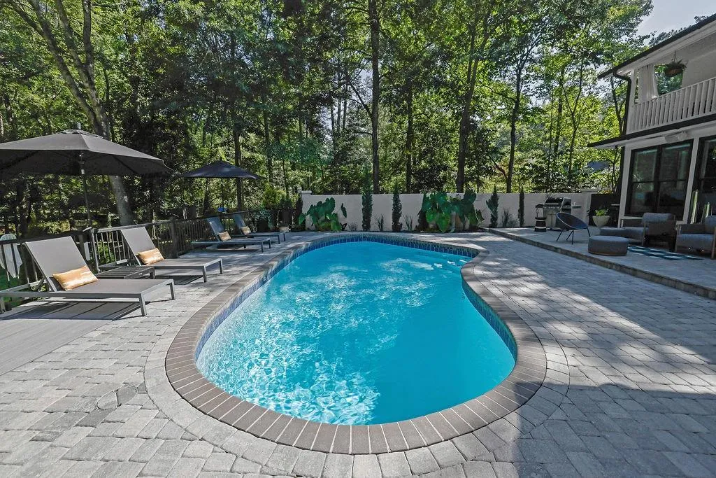 View of pool with a patio area, a fenced backyard, a balcony, and view of scattered trees
