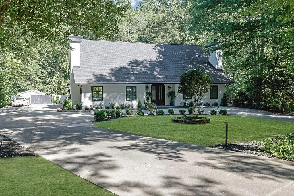View of front of home with a chimney, covered porch, driveway, and stucco siding