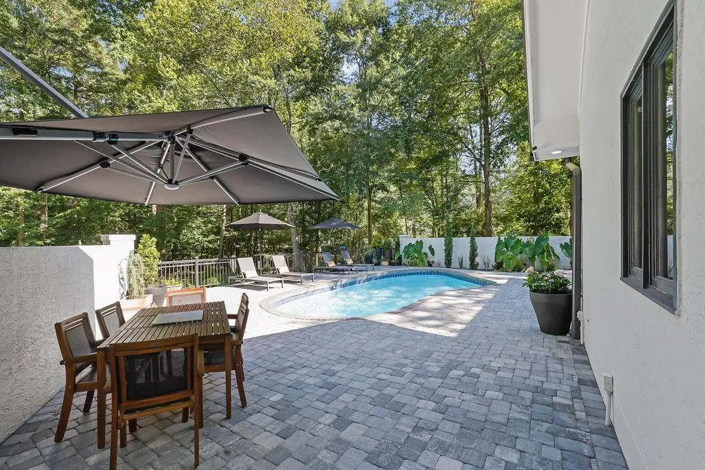 View of pool with a patio, view of wooded area, a fenced backyard, and outdoor dining space