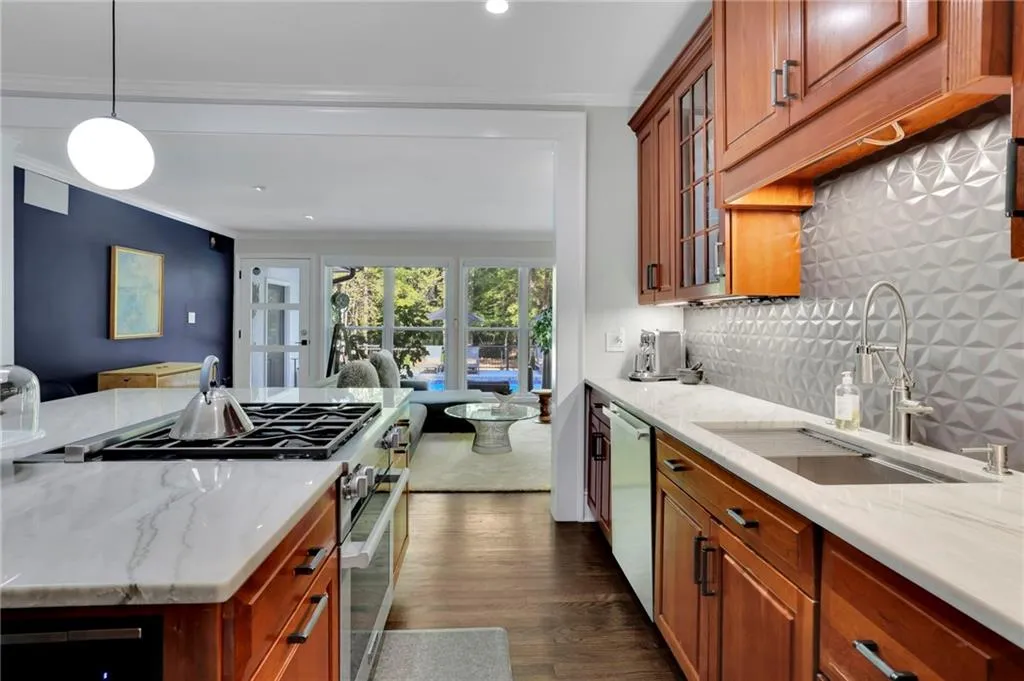 Kitchen featuring beverage cooler, brown cabinets, appliances with stainless steel finishes, a center island, and dark wood-style floors