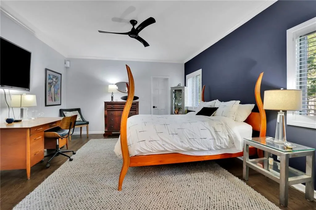 Bedroom featuring dark wood-style floors, ornamental molding, a ceiling fan, and an office area
