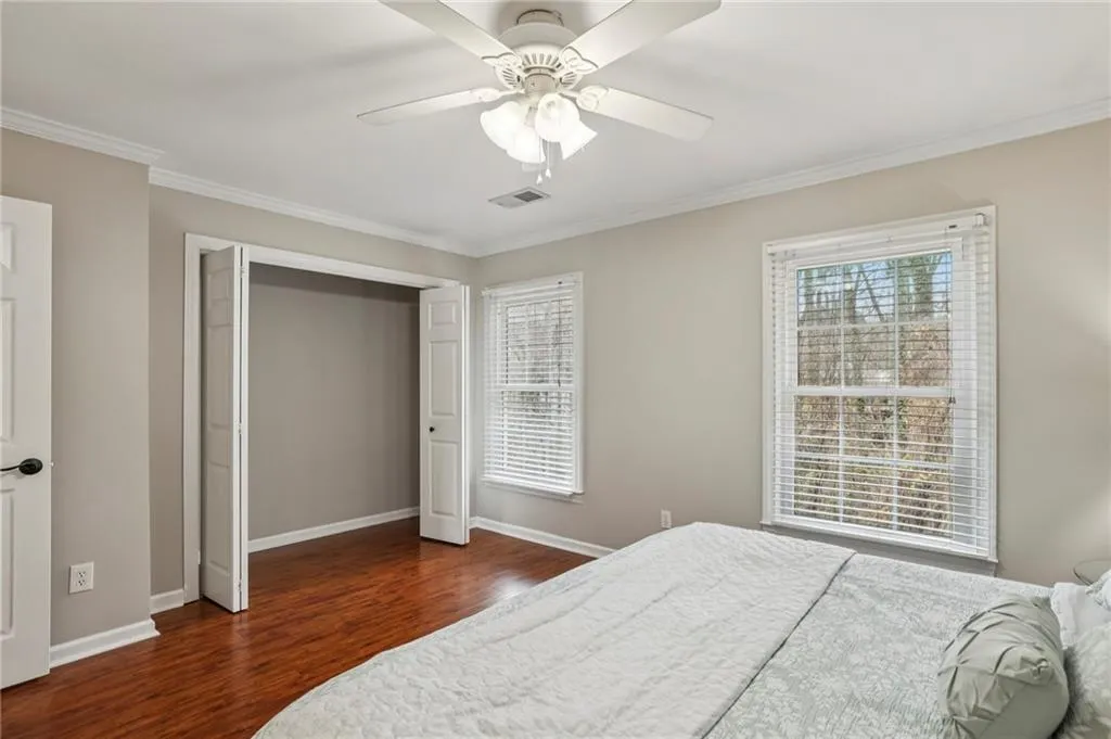 Bedroom with ornamental molding, dark wood-style flooring, ceiling fan, and a closet