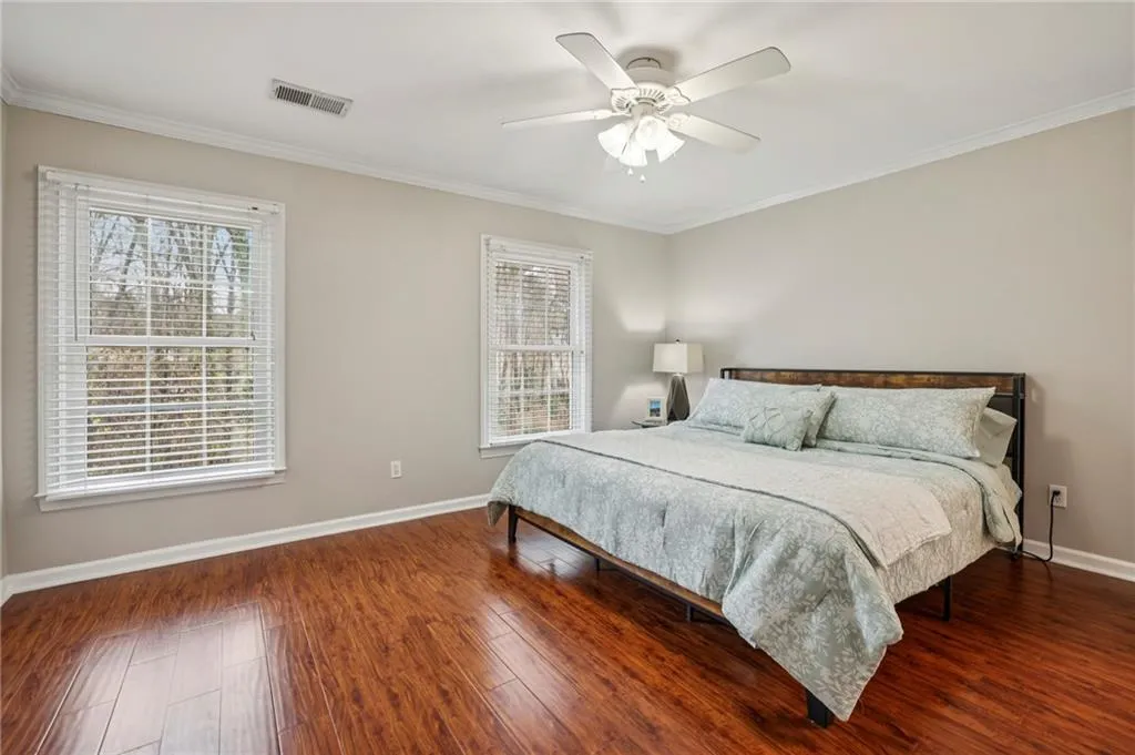 Bedroom with crown molding, dark wood-style flooring, and a ceiling fan