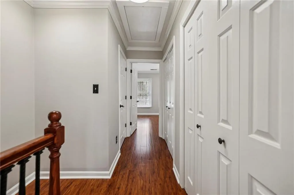 Hallway with dark wood finished floors, crown molding, and an upstairs landing