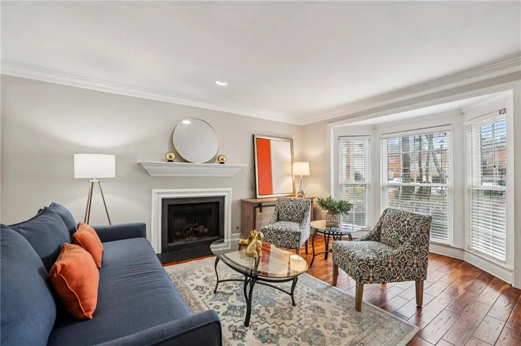 Living room featuring ornamental molding, a fireplace with flush hearth, wood-type flooring, and recessed lighting