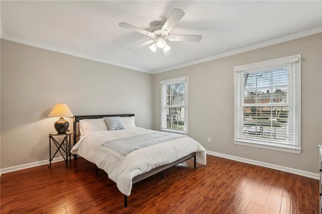 Bedroom with crown molding, dark wood-type flooring, and ceiling fan