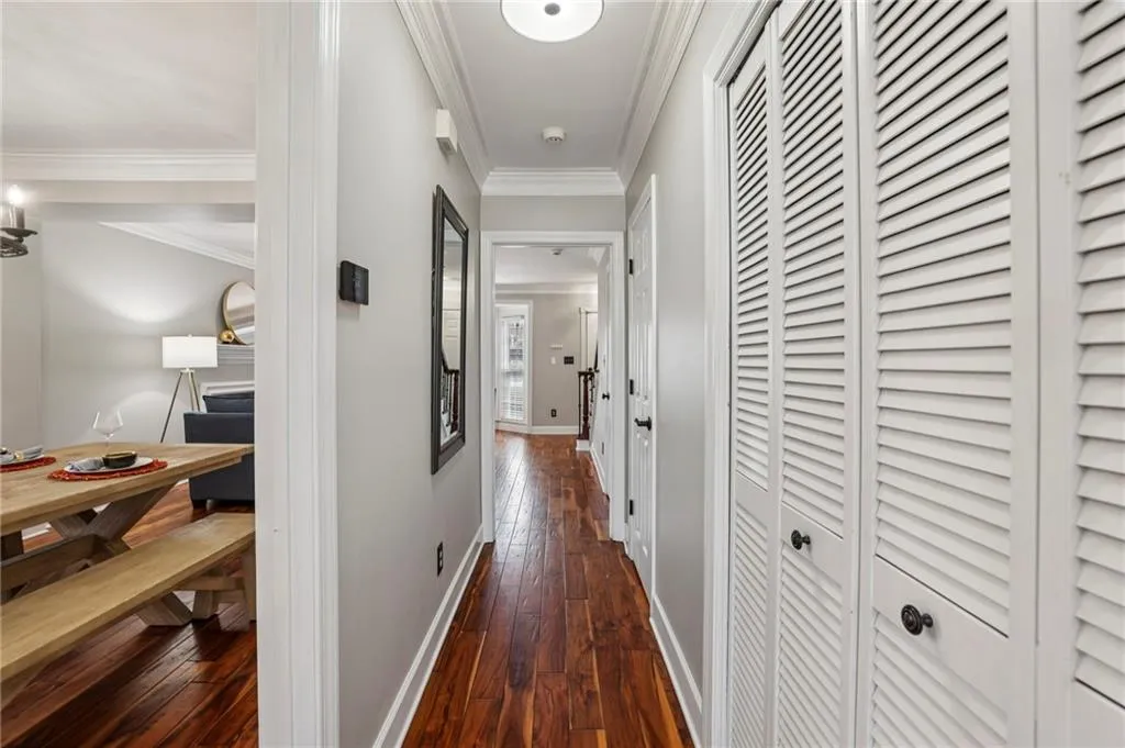 Corridor with dark wood-style flooring and crown molding