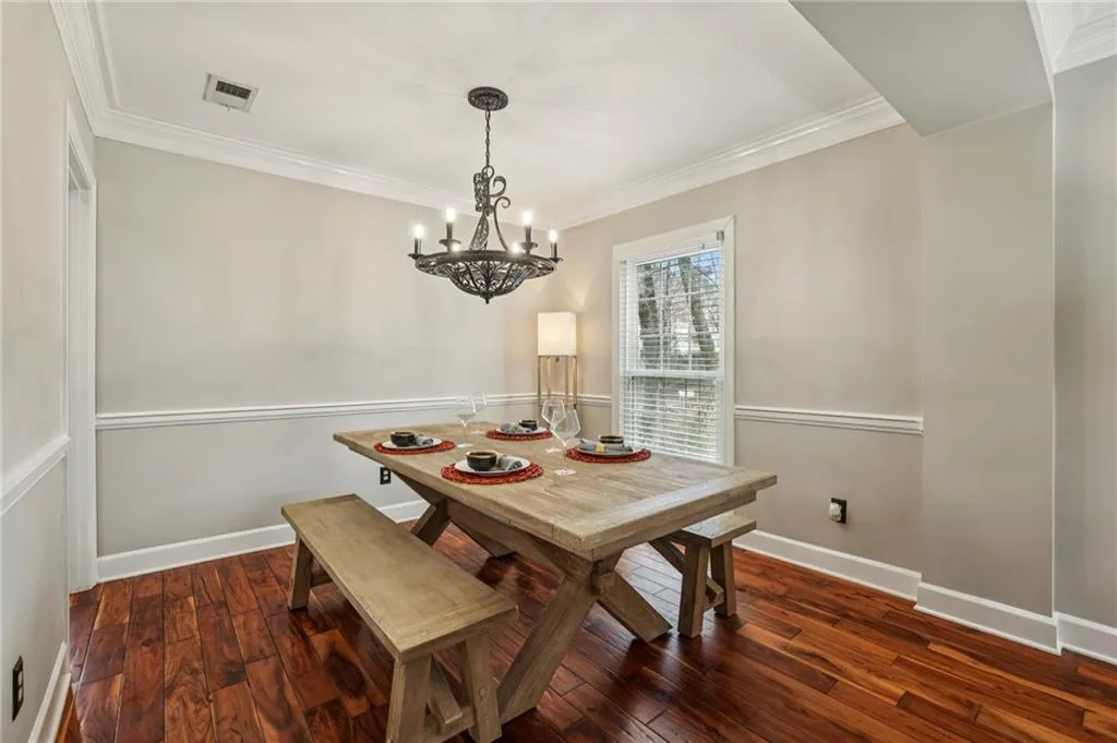 Dining area with dark wood-style flooring, ornamental molding, and hanging lights