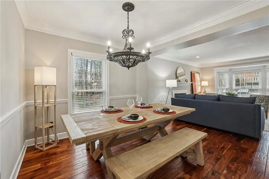 Dining room with dark wood-style floors, crown molding, a fireplace, and suspended lighting