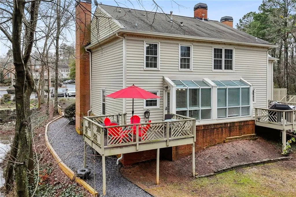 Rear view of house with a chimney, a deck, and a shingled roof