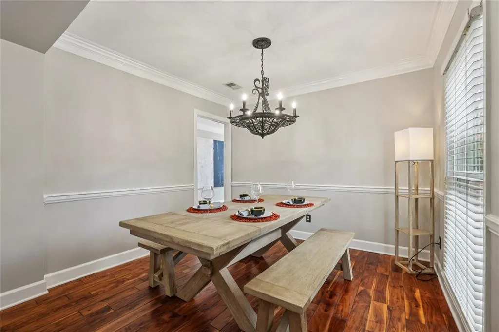 Dining space featuring dark wood-style floors, crown molding, and suspended lighting
