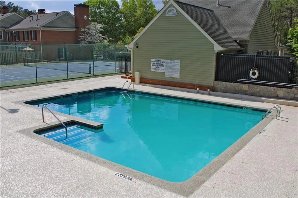Community pool with a patio area and a tennis court
