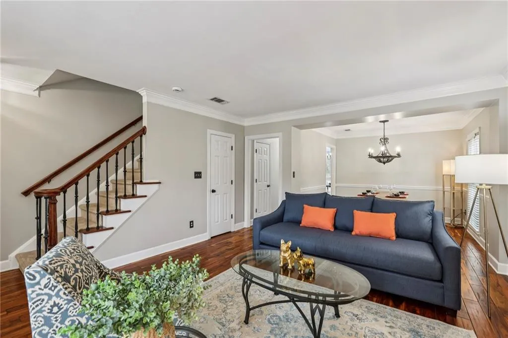 Living room with ornamental molding, hardwood / wood-style flooring, and suspended lighting