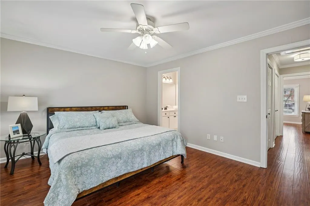 Bedroom featuring crown molding, dark wood-style flooring, and a ceiling fan