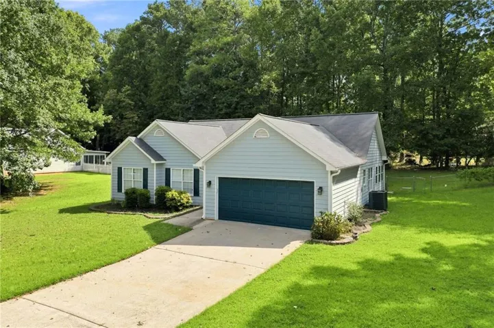 Light blue siding exterior with dark blue garage door, concrete driveway, and established landscaping