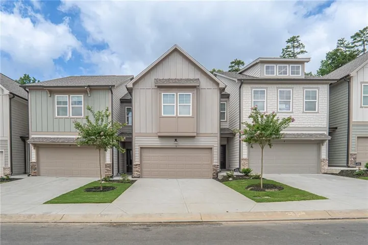 Contemporary townhome exterior featuring a neutral color palette, board-and-batten siding, a single-car garage, and a peaked roofline