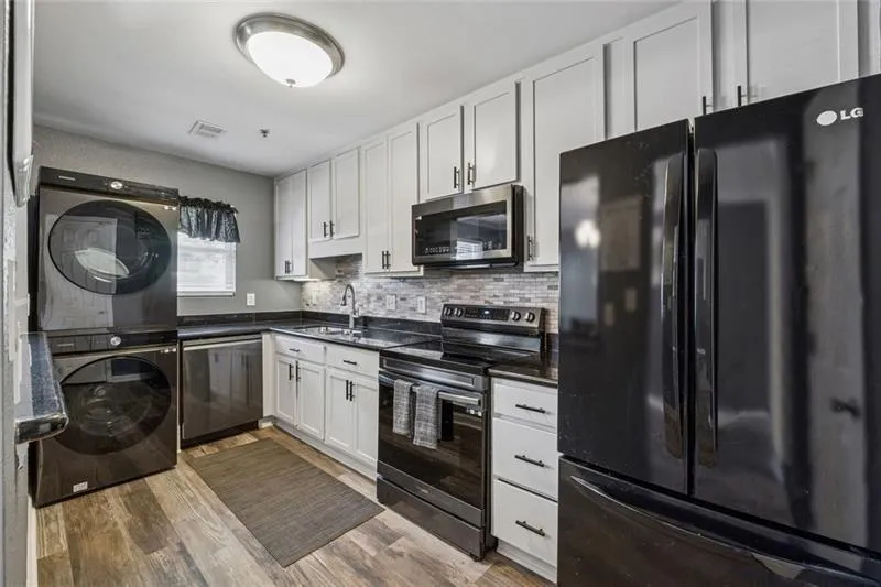 Kitchen with appliances with stainless steel finishes, decorative backsplash, white cabinets, and dark wood finished floors