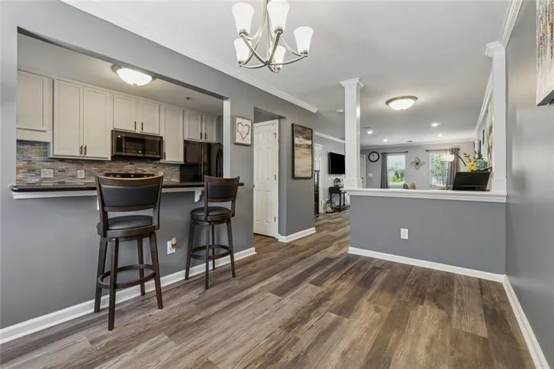 Kitchen featuring a peninsula, a kitchen breakfast bar, ornamental molding, backsplash, and dark countertops