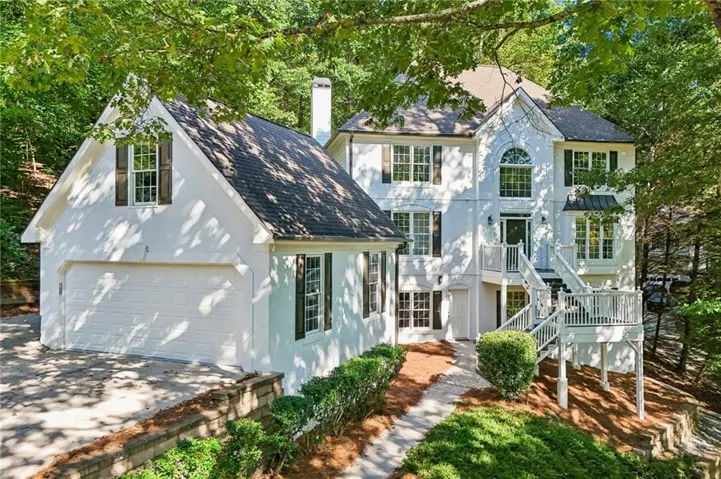 White multi-level exterior with an attached garage, multiple windows, and a prominent front entrance with a balcony