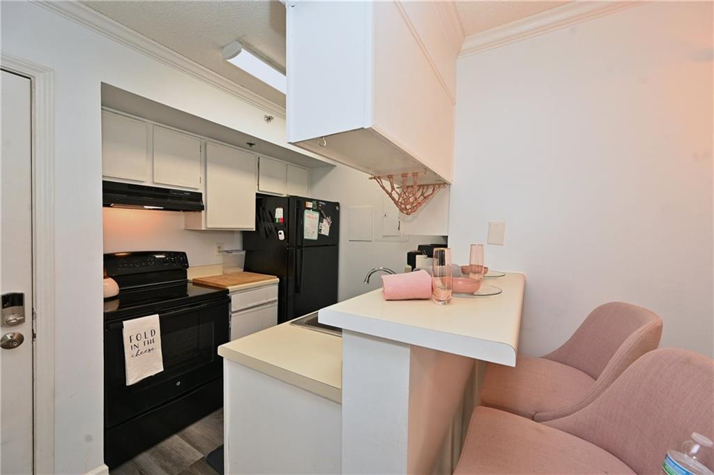 Kitchen featuring black appliances, a breakfast bar area, crown molding, sink, and dark hardwood / wood-style floors
