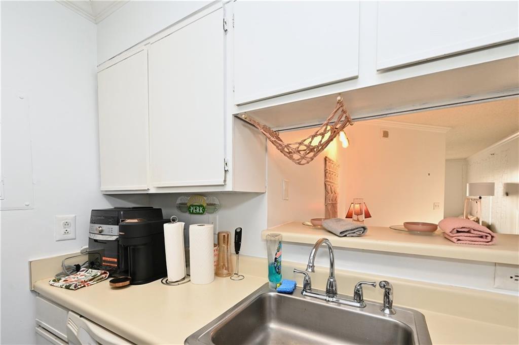 Kitchen featuring sink, dishwasher, crown molding, and white cabinetry
