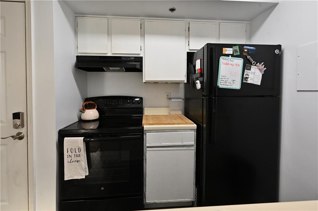 Kitchen featuring white cabinetry, range hood, and black appliances