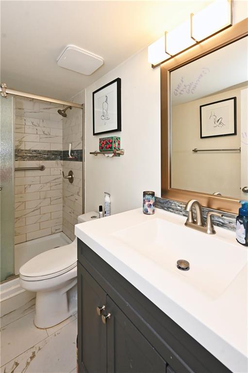 Bathroom featuring a shower with shower door, tile floors, oversized vanity, and toilet