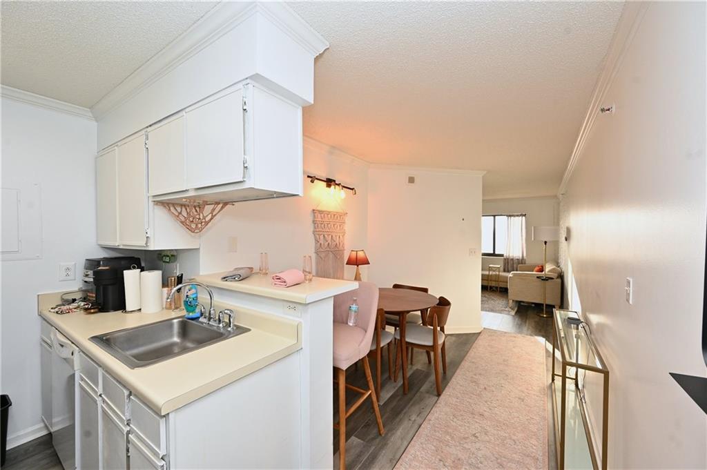 Kitchen featuring white cabinets, dark hardwood / wood-style flooring, sink, and crown molding