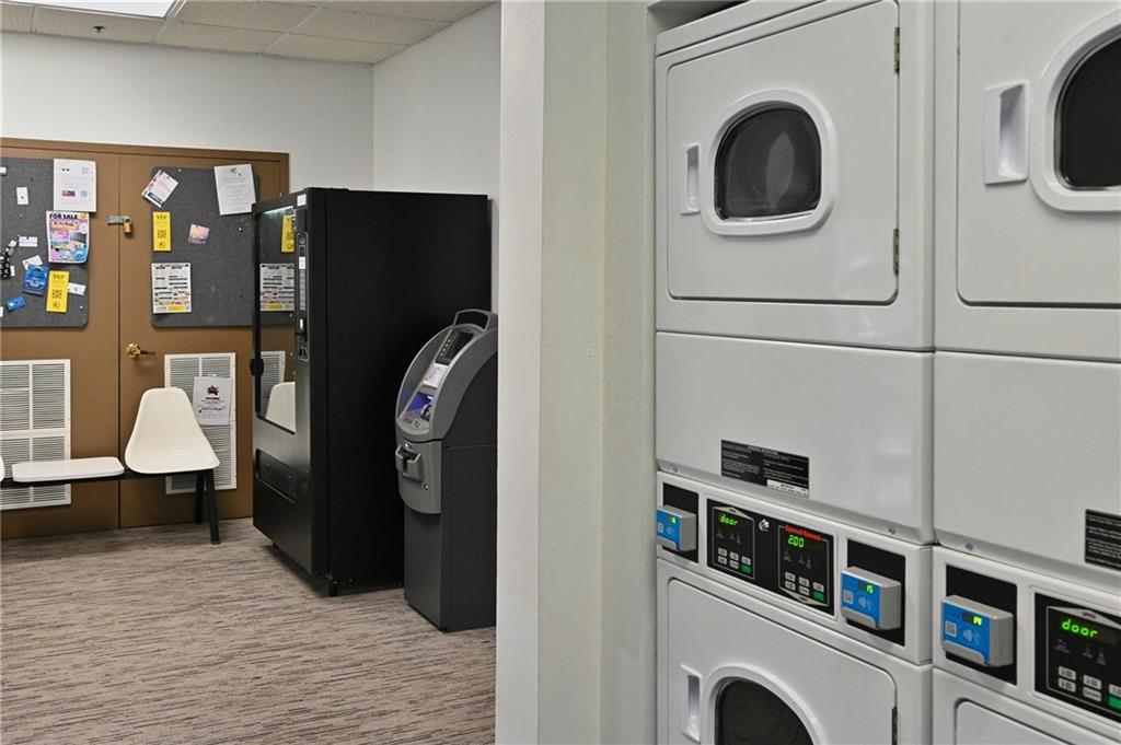 Laundry area featuring stacked washer / dryer and light colored carpet