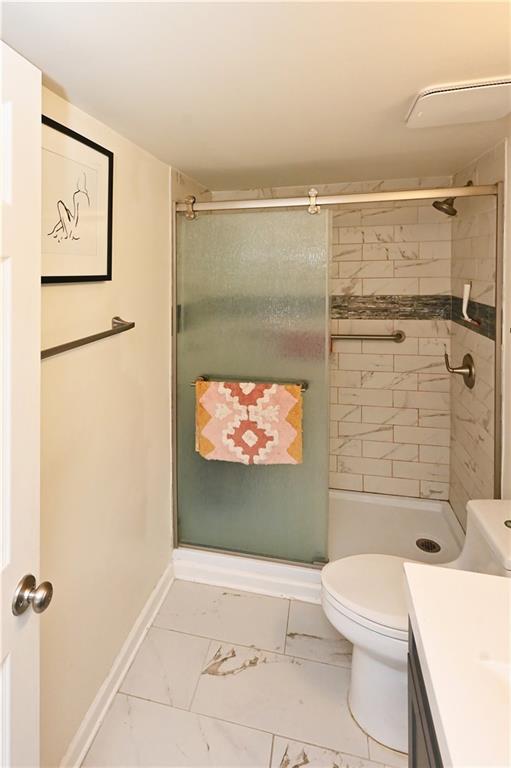 Bathroom featuring vanity, toilet, an enclosed shower, and tile flooring