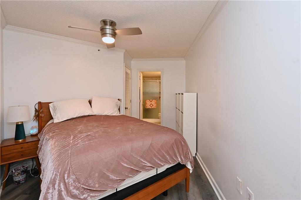 Bedroom with connected bathroom, ornamental molding, ceiling fan, a closet, and dark hardwood / wood-style floors