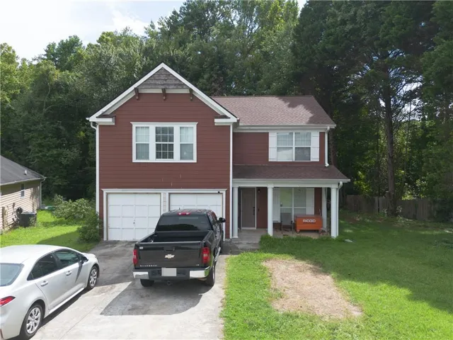 Two-story residence featuring a brown siding exterior, a front-facing attached two-car garage, and a covered front porch with white columns