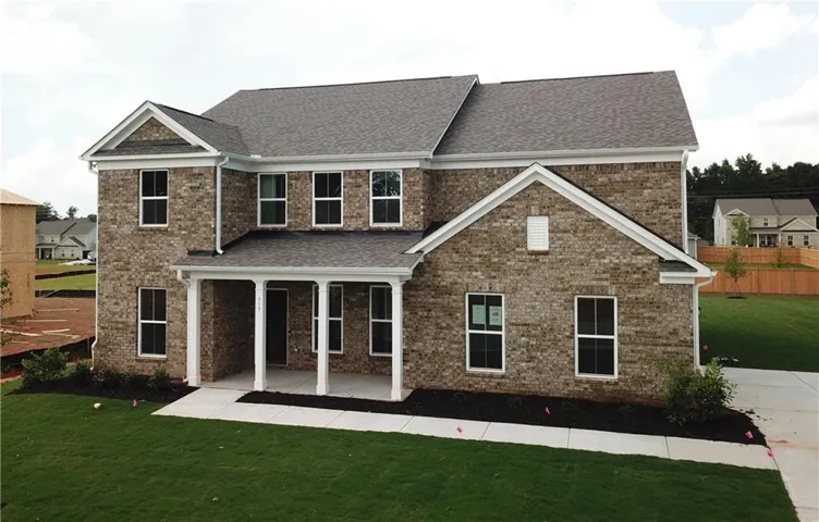 Two-story traditional residence featuring brick masonry, a covered porch with white columns, a gabled roofline, and a paved driveway