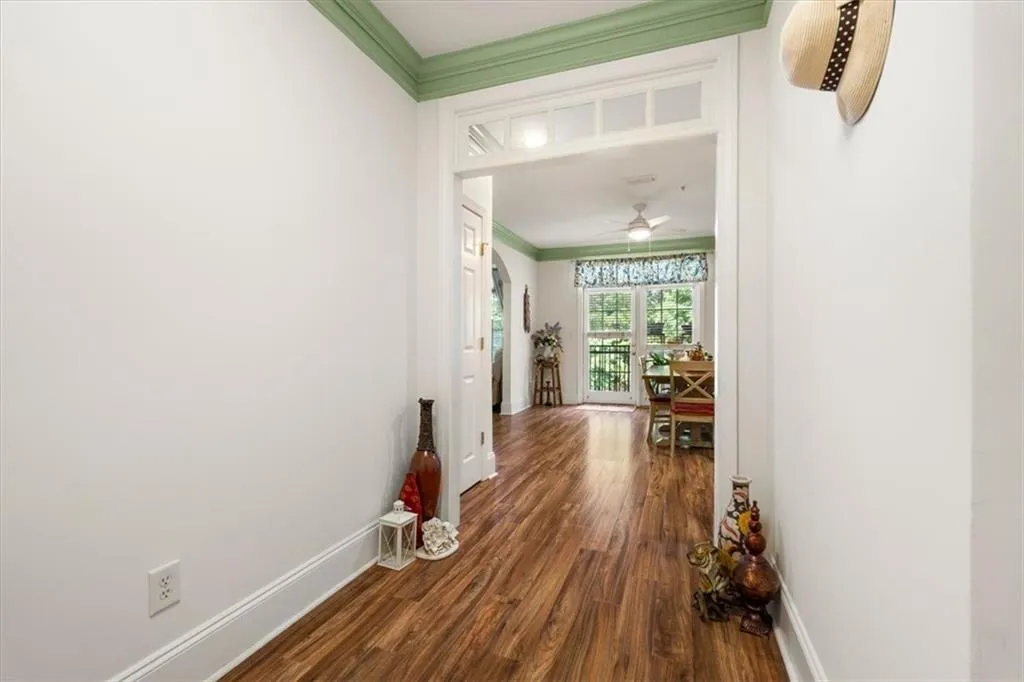 Entryway featuring wood-finish flooring, white walls, and green crown molding