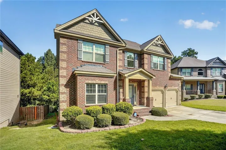 Brick exterior featuring a two-car garage, covered porch entry, and gabled rooflines with decorative accents